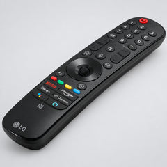 Black LG remote control on a wooden surface with greenery in the background
