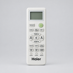 A Haier air conditioner remote control with a white plastic body, green buttons, and a small LCD screen, shown against a plain gray background.