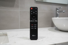 LG remote control on a wooden surface with 'Remote Hut' branding.